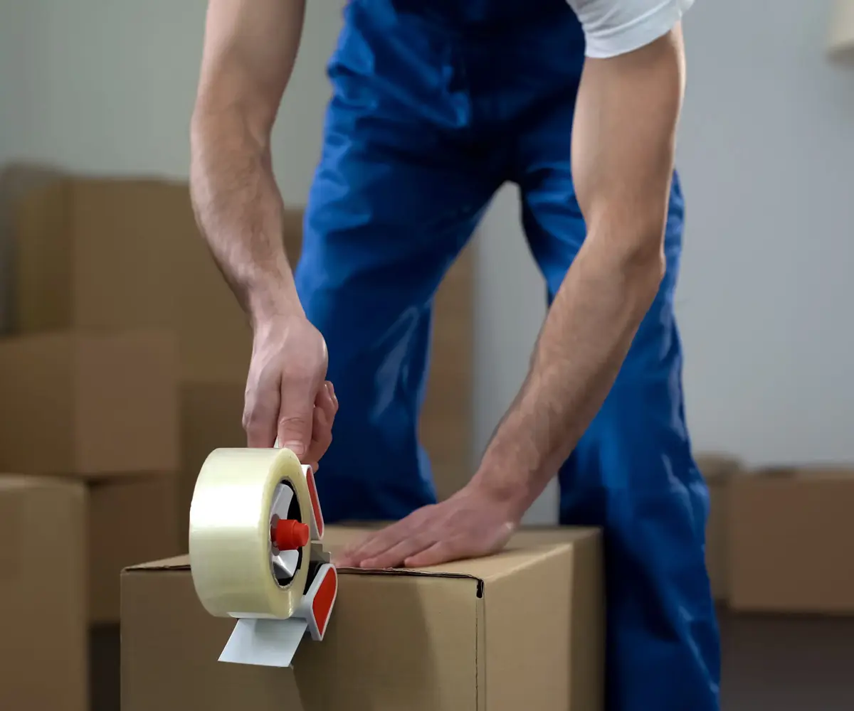 Mover sealing moving box with packing tape – Moving Pro Dallas